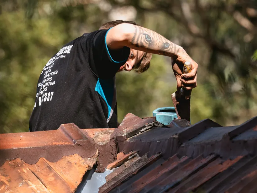Roof plumber repairing terracotta roof tiles