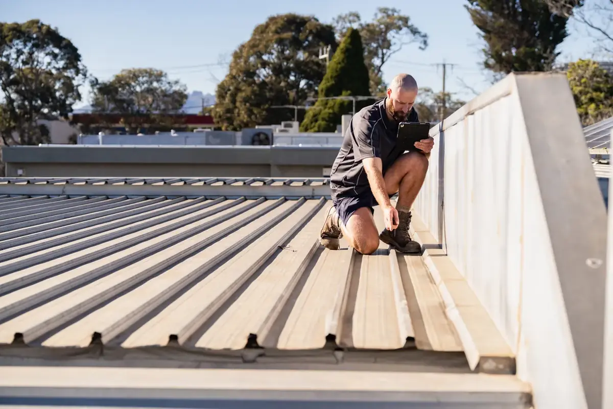 Roofer checking a new metal roof against a parapet wall